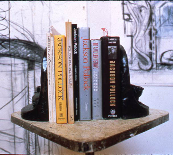 Books about Pollock being held by Saga of Jackson Pollock Bookends, 1990.